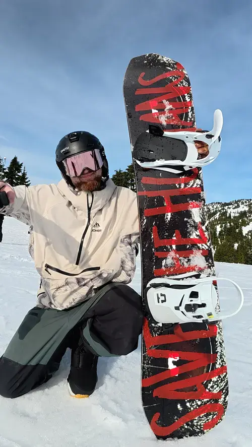 Union Atlas Step On 2026-2027 On Snow Demo | Snowboarding Profiles Nate with Atlas Step On bindings on snowboard kneeling in the snow, snowy mountains in the background